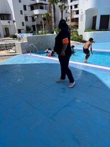 a woman standing in front of a swimming pool at Les dunes de martil familles in Martil