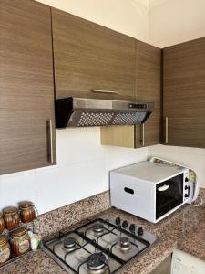 a kitchen with a microwave and a stove top oven at Les dunes de martil familles in Martil