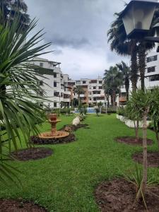 a park with a fountain and palm trees and buildings at Les dunes de martil familles in Martil