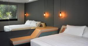 a small room with two beds and a window at Uniko Living Roma in Mexico City