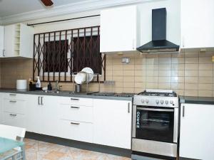 una cucina con mobili bianchi e un forno a piano cottura di Arifas Homes a Accra
