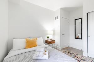 a white bedroom with a large bed with orange pillows at Stylish 3BR Condo near High Park Trails Nearest Intersection Dundas St W in Toronto +14 photos