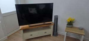 a flat screen tv on a stand in a living room at Foxys Seaside Retreat in Withernsea