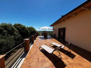 a deck with two chairs and an umbrella on a building at Podere Campanella in Sinalunga