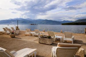 Apartmani Zaliv في تيفات: مجموعة من الكراسي والطاولات بجانب جسم ماء