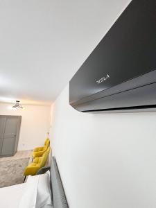 a hotel room with a television and yellow chairs at Skystay-modern Airport Apartment in Cluj-Napoca
