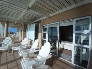 un grupo de sillas blancas sentadas en un porche en Beachfront Family Luxury Rental, en Swakopmund