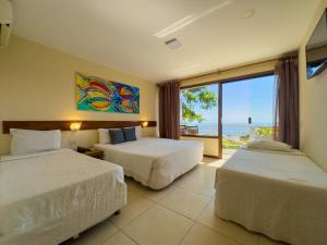 two beds in a room with a view of the ocean at Pousada Amancay in Búzios