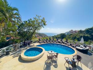 a swimming pool with chairs and a table on a balcony at Pousada Amancay in Búzios