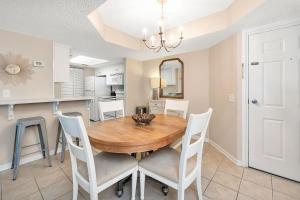 a dining room with a wooden table and white chairs at Beach Club #223 in Saint Simons Island