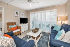 a living room with blue couches and a tv at Beach Club #223 in Saint Simons Island
