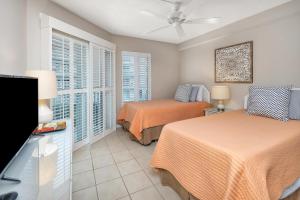 a bedroom with two beds and a flat screen tv at Beach Club #223 in Saint Simons Island +28 photos
