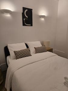 a bedroom with a bed with white sheets and pillows at Appartement cosy aux portes de Paris in Bois-Colombes