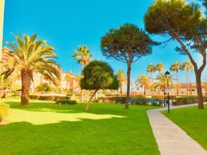 a park with palm trees and a sidewalk at Alcaraván, Isla Canela - By AC REAL in Isla Canela