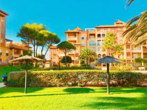 a park with umbrellas in front of a building at Alcaraván, Isla Canela - By AC REAL in Isla Canela +55 photos