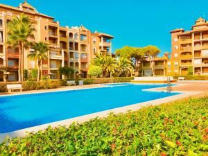 a swimming pool in front of some apartment buildings at Alcaraván, Isla Canela - By AC REAL in Isla Canela