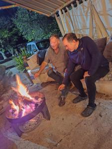 two men sitting next to a fire pit at 2 Wheels Granada Motocamp in Vallequemado