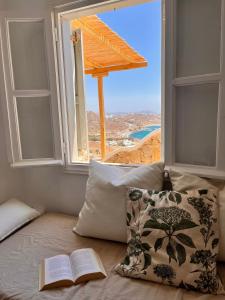 a bed with an open window with an open book at Akra in Houlakia +8 photos