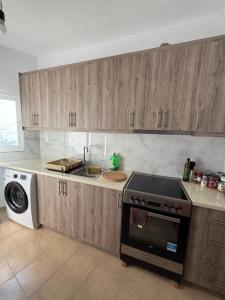 a kitchen with wooden cabinets and a stove top oven at Kolagji Rooms in Lukovë