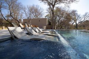 a pool of water with a bunch of chairs in it at Mologa River Lodge in Rust de Winter