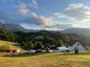 a house on a hill with cars parked in a field at The Alpine Poolhouse in Trnovo