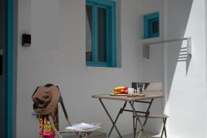 a table and chair next to a wall with blue windows at Kimolos Arch House in Kimolos