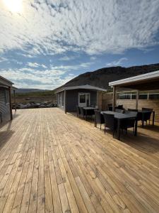 a large wooden deck with tables and chairs on it at Strönd Guesthouse in Birkimelur 