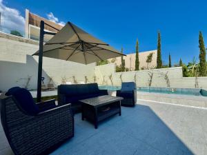 a patio with two chairs and a table with an umbrella at Elite Vila with Pool, Green Coast in Palasë