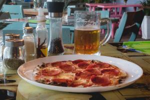 a pepperoni pizza on a table with a mug of beer at Hotel Barahona Cartagena in Cartagena de Indias +66 photos