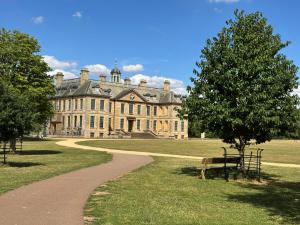 ein Gebäude mit einem Baum und einer Bank in einem Park in der Unterkunft Sunny Cottage in Grantham
