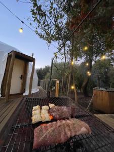 einen Grill mit Fleisch und anderen Lebensmitteln darauf in der Unterkunft Glamping III Domo 7 Tazas con Tinaja in Molina
