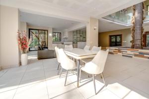 Un comedor con una mesa y sillas blancas. en Guest House by Atholl, en Johannesburgo