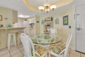 une salle à manger avec une table en verre et des chaises blanches dans l'établissement Beach Club #313, à Île de Saint-Simon