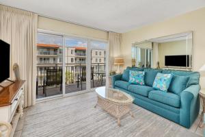 un salon avec un canapé bleu et une télévision dans l'établissement Beach Club #313, à Île de Saint-Simon