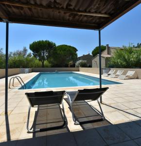 a swimming pool with a table and two chairs at Mas de la Tour Carbonnière in Aigues-Mortes