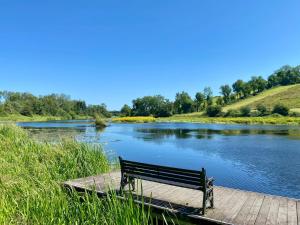 a bench sitting on a dock next to a river at Luxury Waterfront Retreat I Deluxe Lodge I Private Hot Tub & Sauna in Belturbet