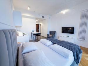 a bedroom with a large white bed and a desk at Hanza Tower Apartments Premium in Szczecin