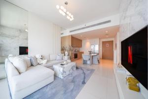 a white living room with a white couch and a tv at Most Luxurious2br Apt Private Beach in Dubai