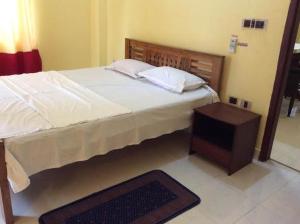 a bedroom with a large bed and a night stand at Redrose Service Apartment in Kannur
