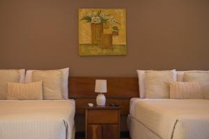 a bedroom with two beds and a painting on the wall at Hotel Diriá Santa Cruz in Santa Cruz