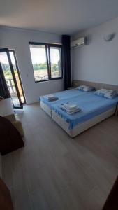 a bedroom with a bed with blue sheets and windows at Lozenets Oasis Beach Home Four in Lozenets