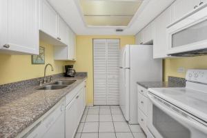 Una cocina blanca con fregadero y refrigerador. en Beach Club #325, en Saint Simons Island