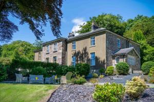 an exterior view of a large brick building with chairs in a garden at Cilrhiw Country House - Princes Gate in Narberth