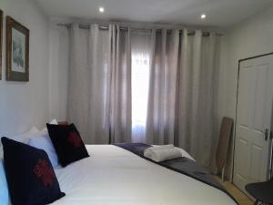 Un dormitorio con una cama con sábanas blancas y una ventana. en Russell's Rest Apartments, en Johannesburgo