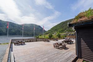 a wooden deck with picnic tables and a body of water at Family Cabins in Fjæra
