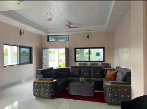 Una sala de estar con un sofá de cuero negro. en Live N Joy Villa Moinabad, en Venkatāpur