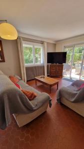 a living room with two beds and a flat screen tv at Villa Les Chênes - Golfe de Saint-Tropez Experience in Port Grimaud
