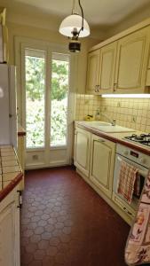a kitchen with white cabinets and a red floor at Villa Les Chênes - Golfe de Saint-Tropez Experience in Port Grimaud +15 photos
