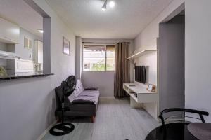 a living room with a couch and a desk in a room at Apto com ar-condicionado e vaga em Honorio Gurgel in Rio de Janeiro