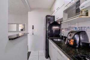 a kitchen with a black refrigerator and a sink at Apto com ar-condicionado e vaga em Honorio Gurgel in Rio de Janeiro